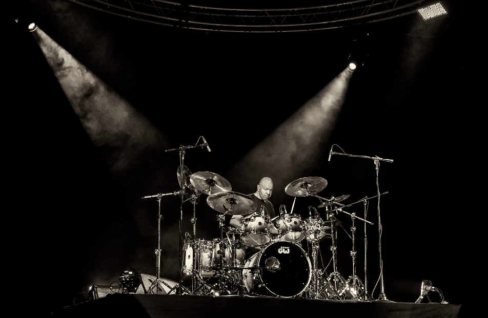 man playing drums solo during a concert.