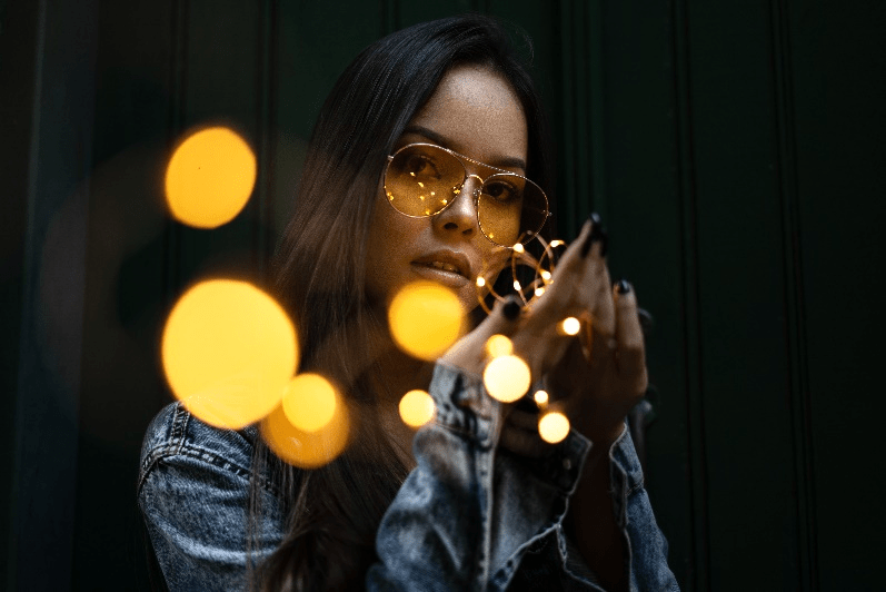 A model wearing double-bridged sunglasses while posing with fairy lights.