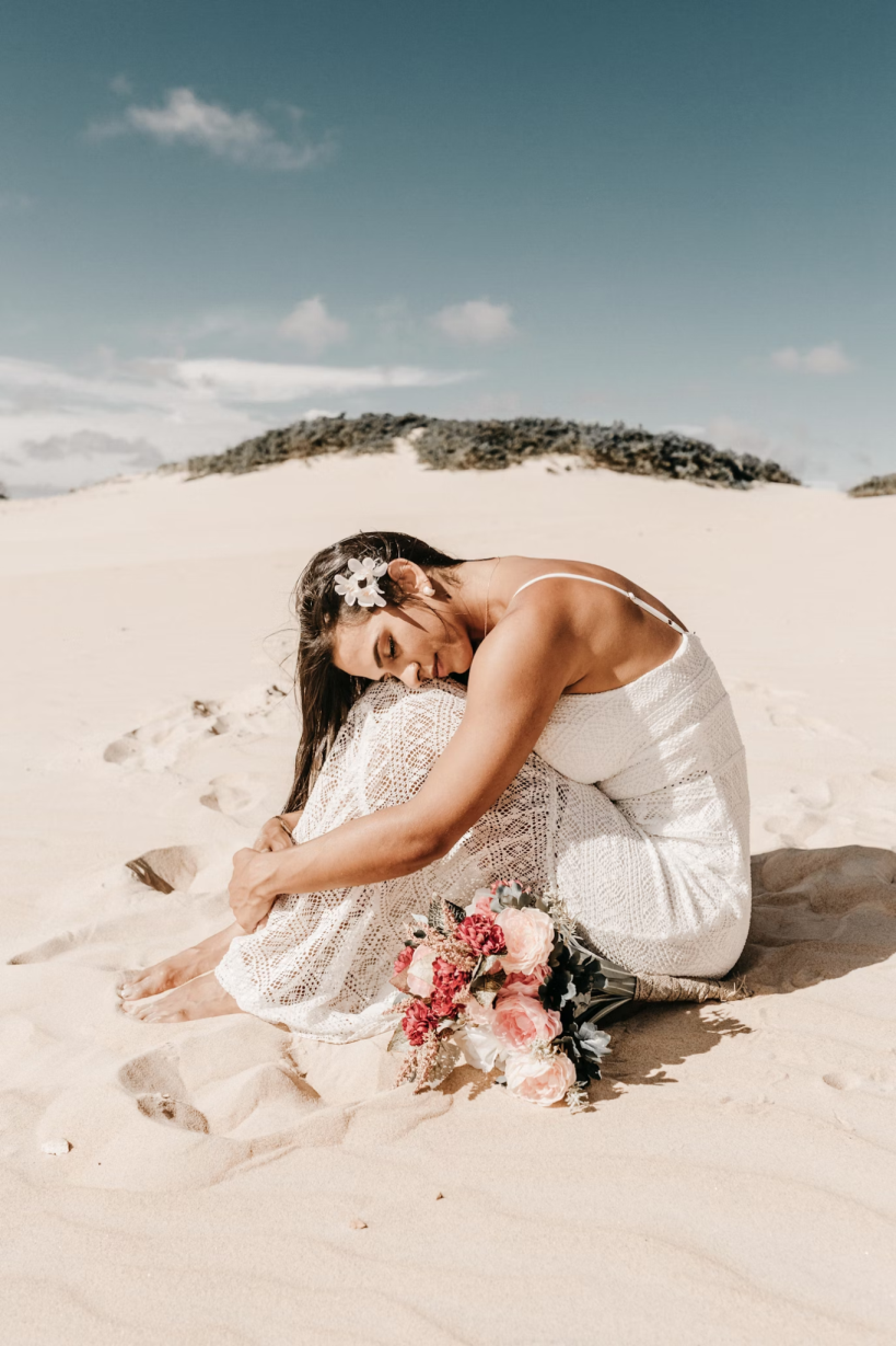 a bride sitting on the beach