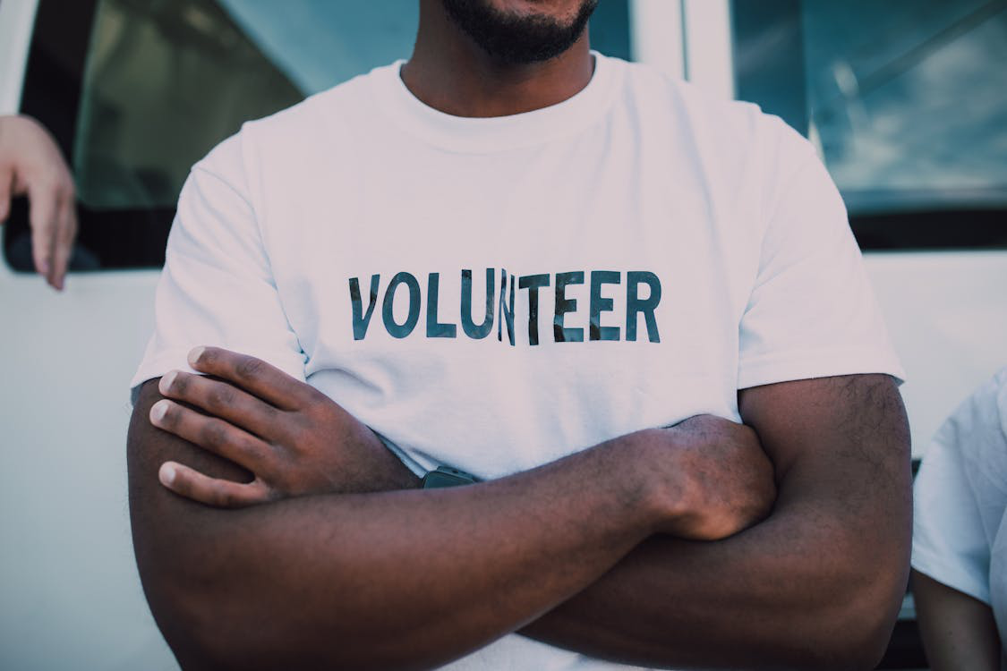 A close-up photo of a person in a white t-shirt with volunteer written on it