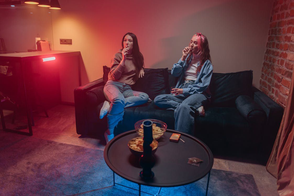 Two girls smoking together on a couch